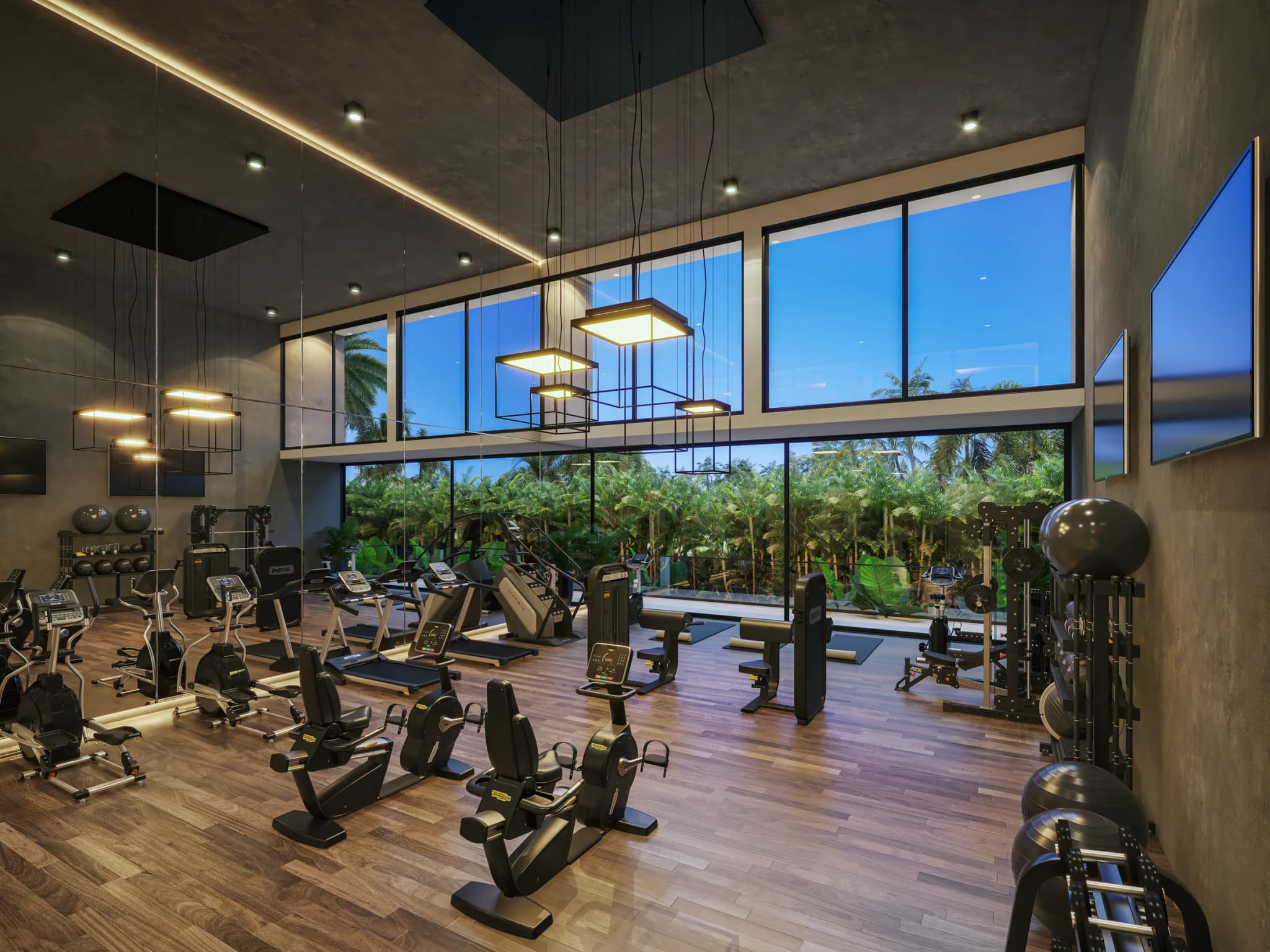 Gimnasio con máquinas de cardio frente a un ventanal hacia la vegetación