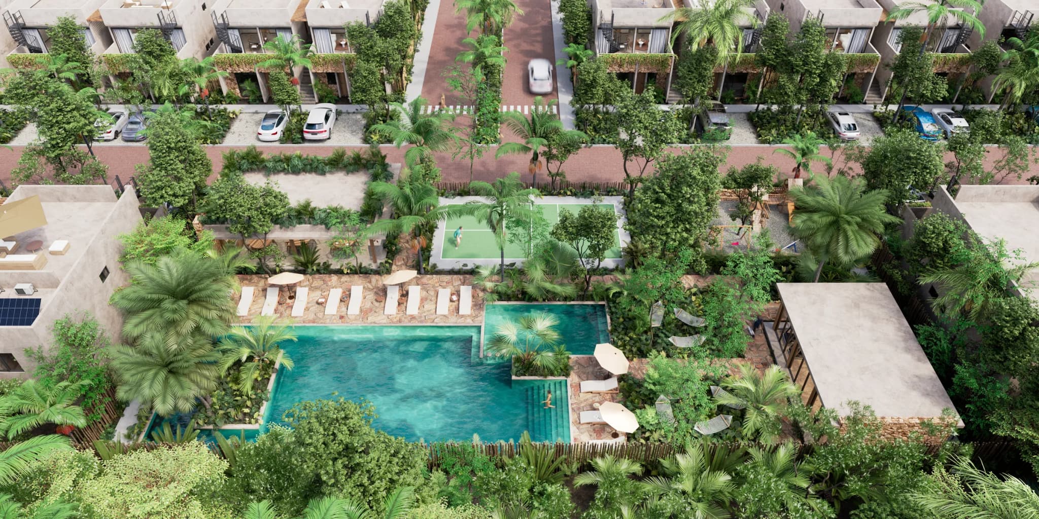Aerial view of the shared area: the pool, sun loungers, pickleball court and gardens among the homes