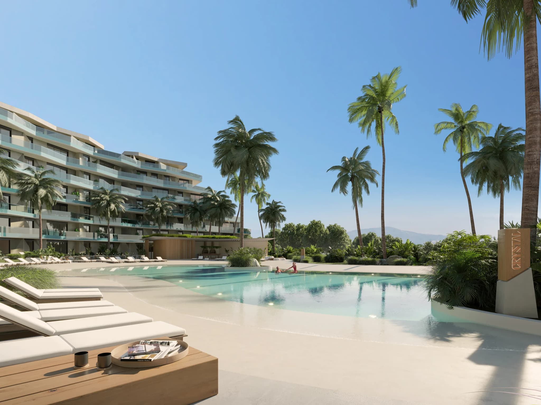 Piscina con playa de arena y tumbonas, con los edificios al fondo